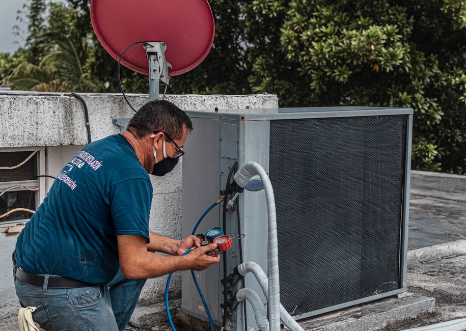 Technician checking refrigerant pressure on an air conditioning unit