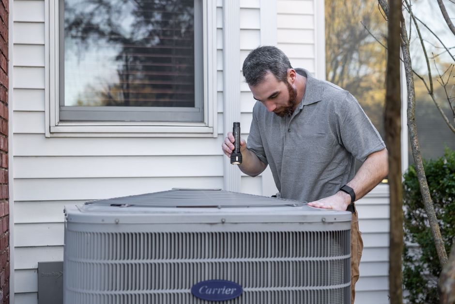 HVAC technician inspecting an outdoor air conditioner condenser unit